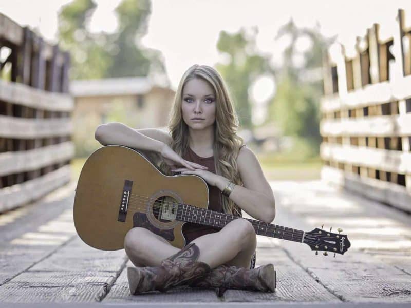 girl sitting cross legged holding acoustic guitar